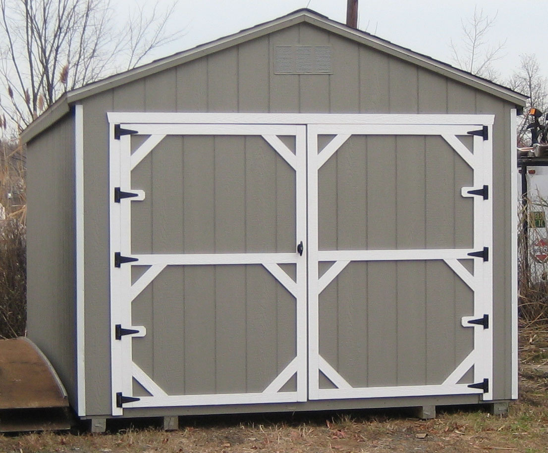 Tan vinyl-sided A-frame garage with a roll-up door and side entry door.