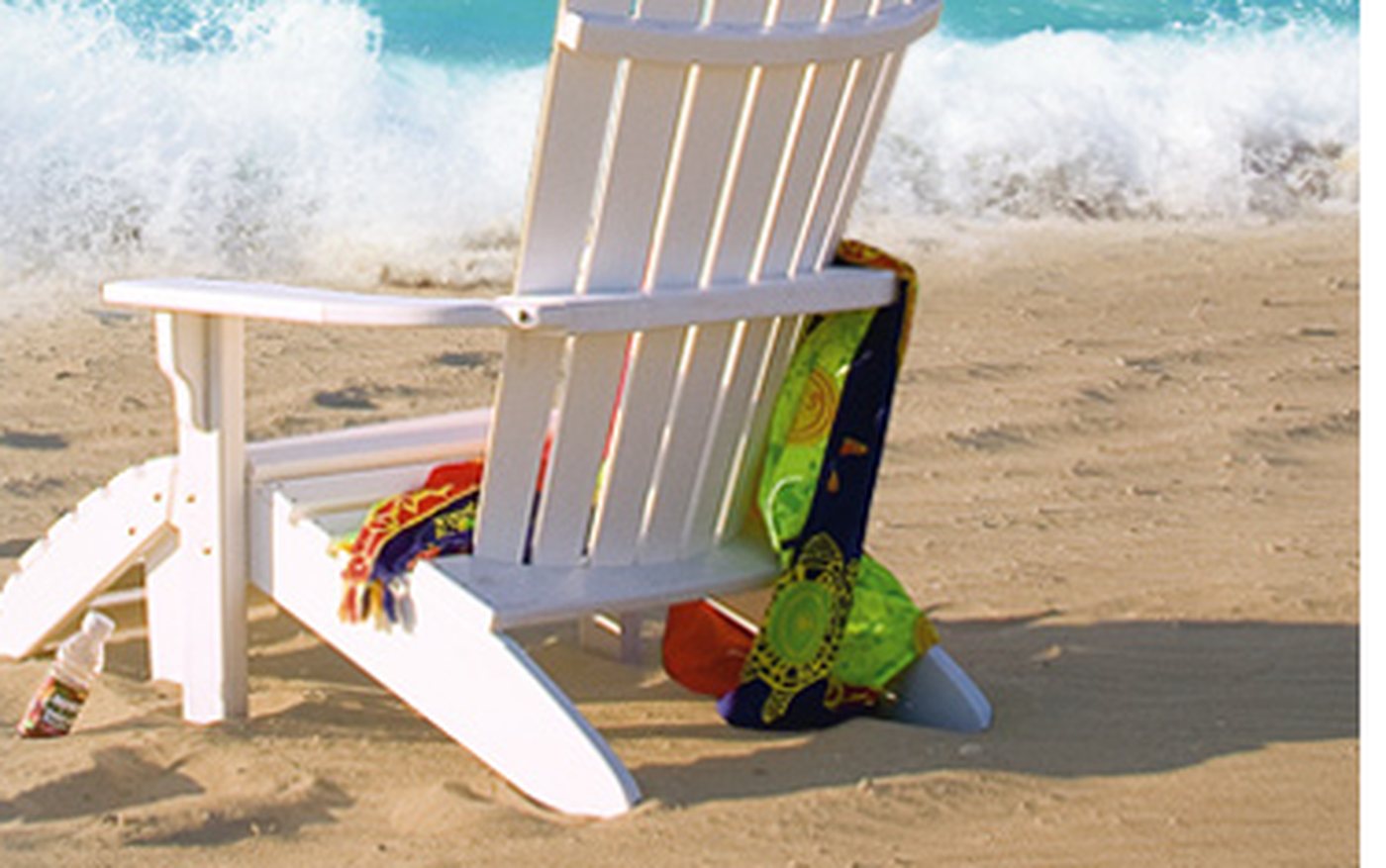 White poly fanback Adirondack chair on a sandy beach.