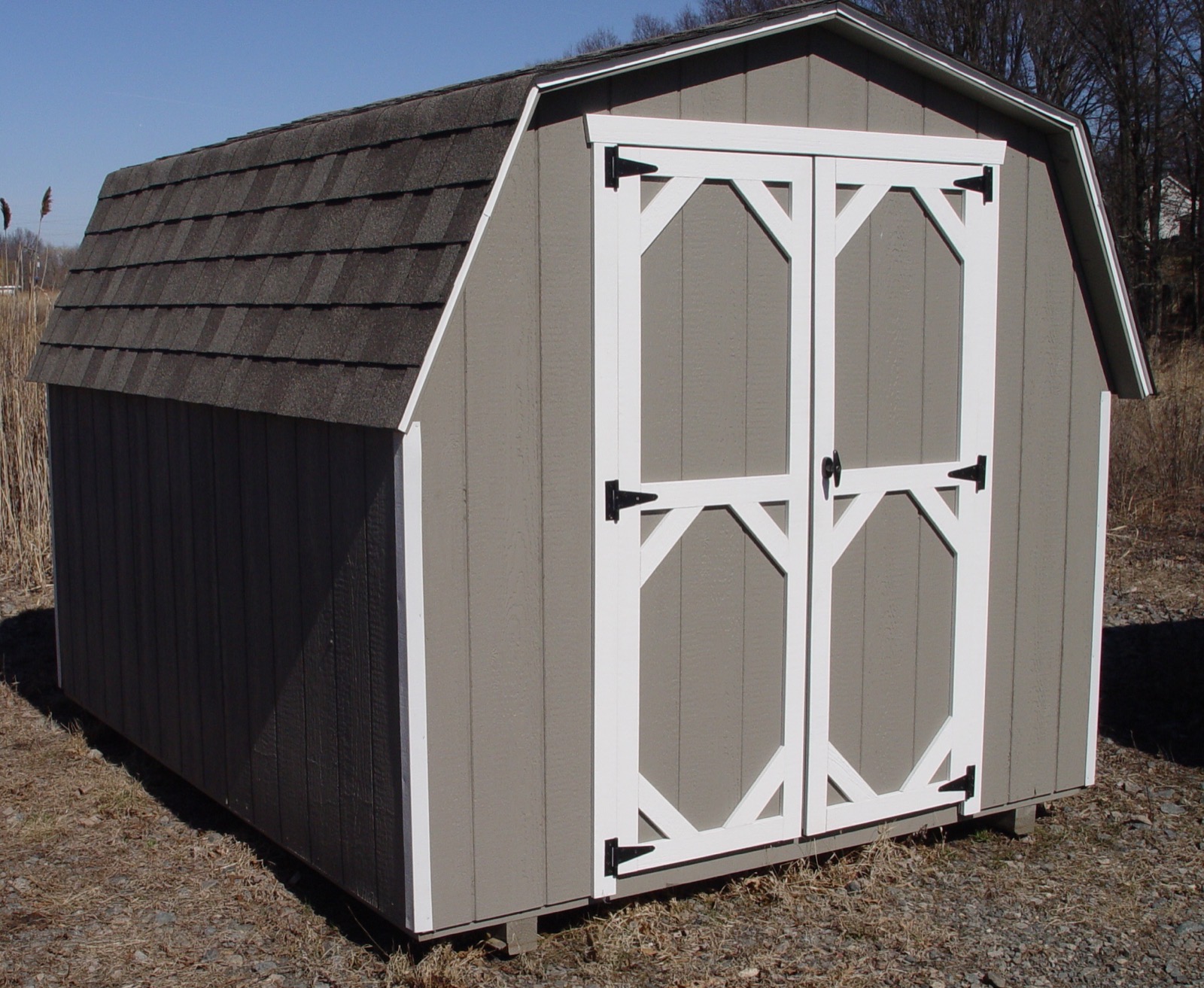 Grey Dutch barn style shed with white trim doors.