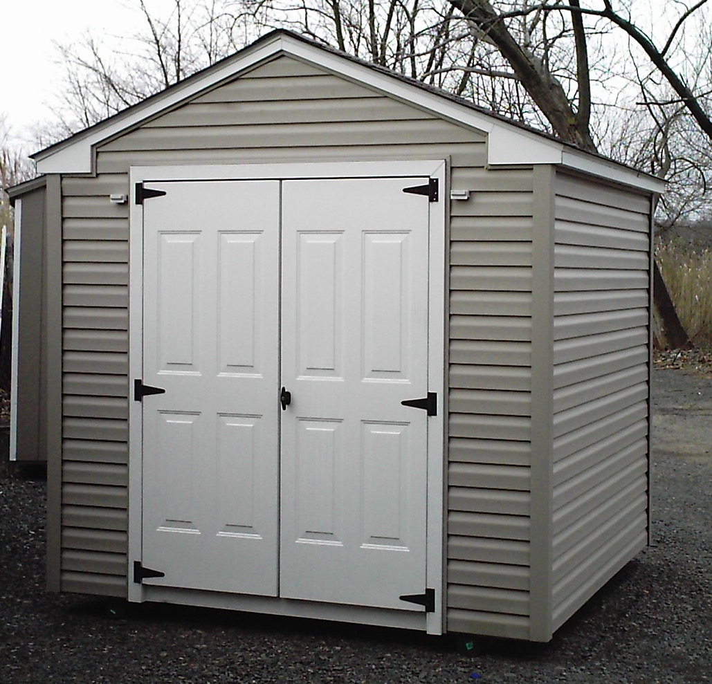 Beige vinyl A-frame shed with a white roll-up garage-style door.